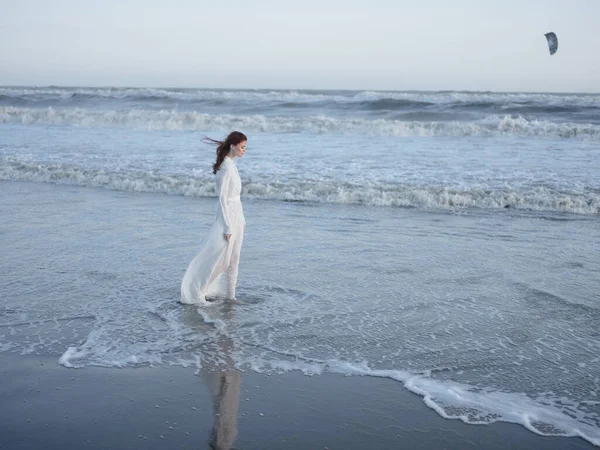 Γυναίκα σε λευκό φόρεμα βόλτες κατά μήκος της ακτής του ωκεανού τοπίο πολυτέλεια — Φωτογραφία Αρχείου