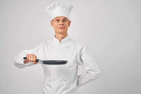 요리사의 옷을 입고 요리 전문가들의 손에 프라이팬을 쥐고 있는 남자 — 스톡 사진