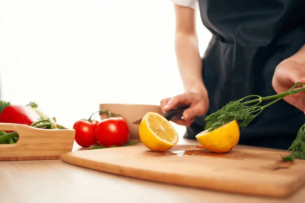 Chef con un cuchillo en las manos corta verduras y limón cocina casera —  Fotos de Stock