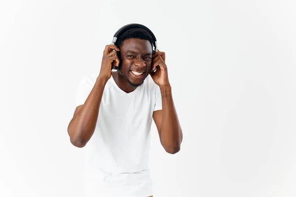 Afrika kökenli bir adam kulaklıklarla beyaz tişört müziği ile ortaya çıktı. — Stok fotoğraf
