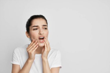 Beyaz tişörtlü, dişleri ağrıyan bir kadın. Yüksek kalite fotoğraf