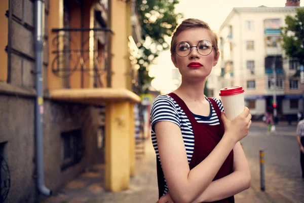 Bonita mujer con gafas de pelo corto al aire libre una taza de bebida — Foto de Stock