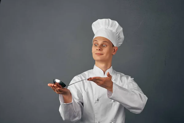 Un uomo in uniforme chef con un mestolo in mano cucinare cibo cucina professionale — Foto Stock