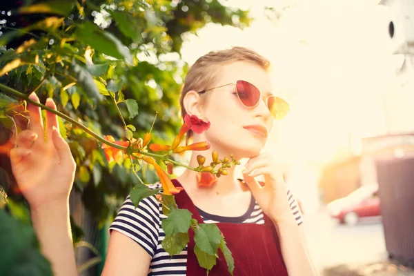Femme aux cheveux courts portant des lunettes de soleil décoration de fleurs en plein air — Photo