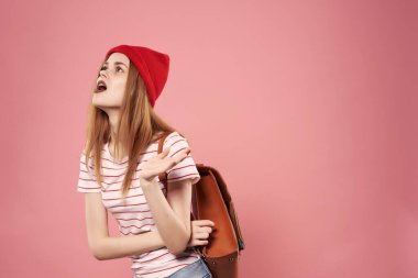 Güneş gözlüğü takan genç, modaya uygun bir kadın. Pembe arka plan pozu veren günlük kıyafetler.