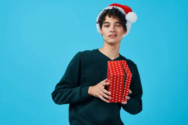 Lindo chico usando santa sombrero regalos partido fondo azul — Foto de Stock