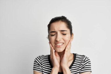 Çizgili tişörtlü kadının elinde diş hekimliği ağrısı var.