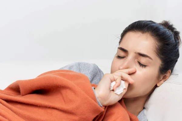 Frau liegt mit geschlossenen Augen auf der Couch und fühlt sich unwohl — Stockfoto