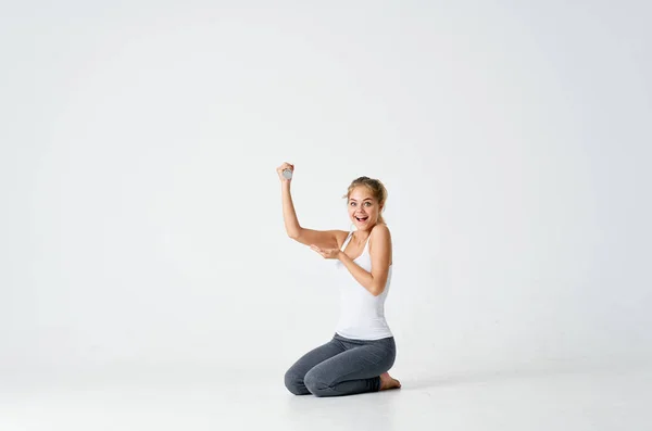Atletyczna kobieta siedzi na podłodze ćwiczenia hantle fitness — Zdjęcie stockowe