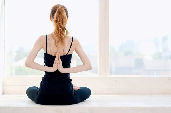 Mujer medita cerca de ventana ejercicio tranquilo — Foto de Stock