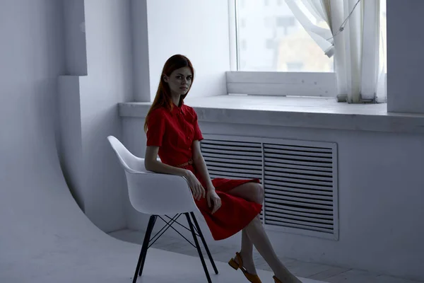 빨간 드레스를 입은 아름다운 여인 이 의자 패션을 입고 있는 모습 — 스톡 사진