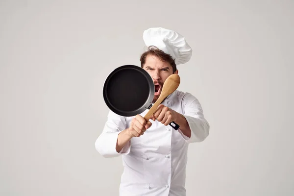 En man i en kocks uniform en stekpanna i händerna matlagning arbete — Stockfoto