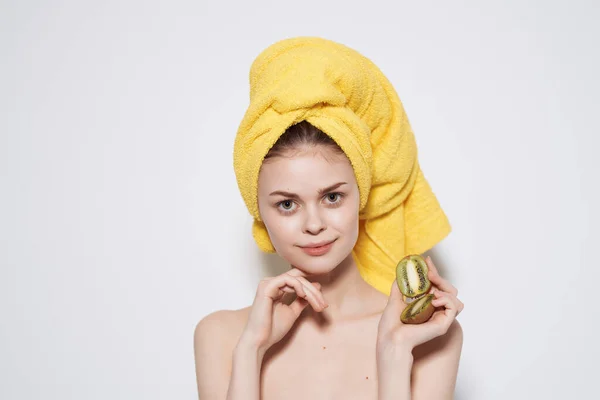Гарна жінка з жовтим рушником на голові голі плечі ківі фрукти — стокове фото