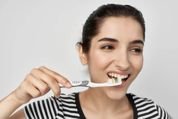 Morena escovar os dentes com uma escova de dentes isolado fundo — Fotografia de Stock
