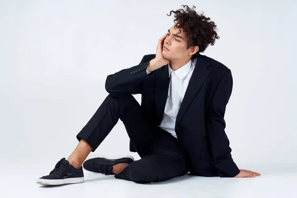 Chlap v černé bundě sedí na podlaze módní elegantní styl — Stock fotografie