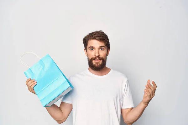 Mężczyzna w białym t-shirt niebieski pakiet zakupy lekkie tło — Zdjęcie stockowe