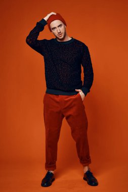 Kırmızı şapkalı adam stüdyo tarzı modern poz veriyor.
