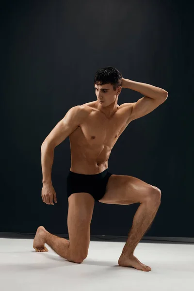Sexy Mann in schwarzen Höschen kniet mit einem aufgepumpten Körperstudio — Stockfoto