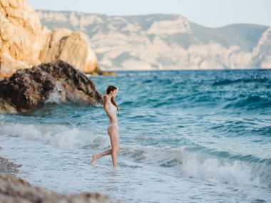 Kadın bikini pozu vererek deniz tatili boyunca yürüyor.