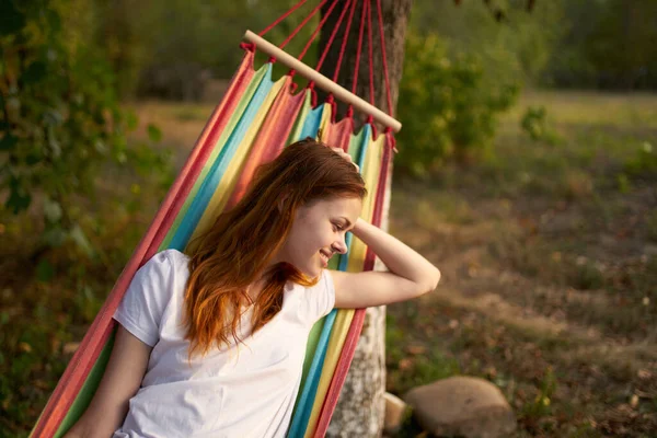 Glad kvinna i naturen ligger i en hängmatta vila komfort — Stockfoto
