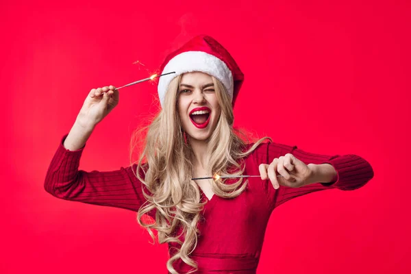 Veselá žena v santa klobouk jiskry Vánoce červené pozadí — Stock fotografie