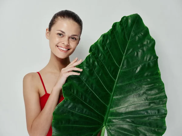 Mulher bonita alegre com folha verde em suas mãos maiô vermelho posando — Fotografia de Stock