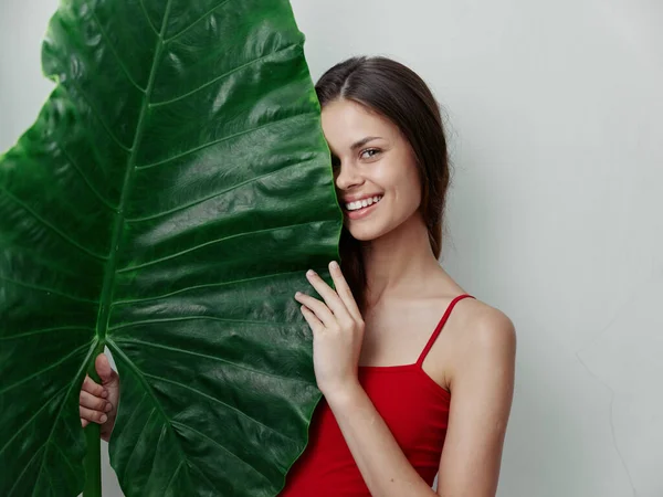 Ağzında mayo olan ve önünde yeşil bir yaprak tutan bir kadın. — Stok fotoğraf