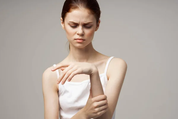 Beyaz tişörtlü kadın kol ağrısı, artrit, kronik hastalık, hafif arka plan. — Stok fotoğraf