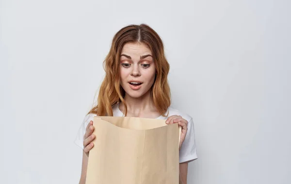 Mulher em uma camiseta branca com um pacote em suas mãos compras — Fotografia de Stock