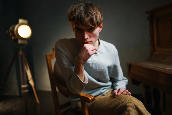 Guy sitting on a chair next to the piano posing photo — Stock Photo, Image