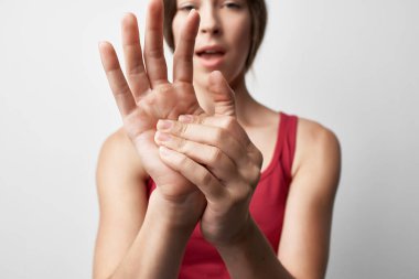 Kırmızı tişörtlü kadın, eklem ağrısı, el tedavisi.