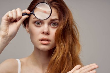 Kızıl saçlı kadın büyüteç, yüz hijyenine yakın çekim.