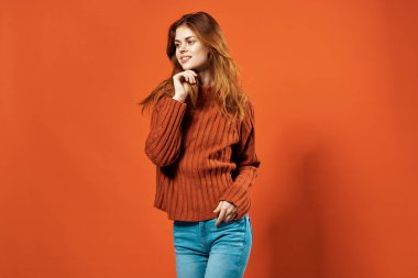 Kırmızı kazaklı neşeli güzel kadın stüdyoda poz veriyor.