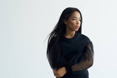 Siyah elbiseli güzel kadın makyajlı uzun saçlı poz veriyor.