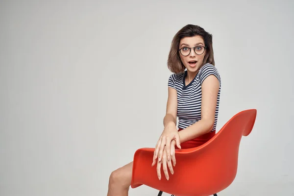 Mulher em uma camiseta listrada sentado na cadeira vermelha corte vista glamour — Fotografia de Stock