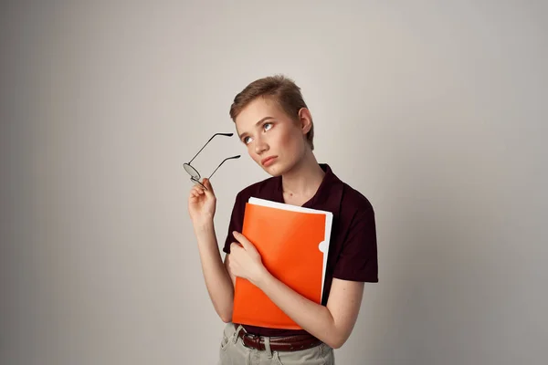 Vacker kvinna med en orange mapp i handen ljus bakgrund — Stockfoto