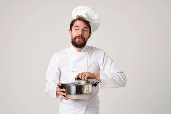 Um homem com um uniforme de cozinha com uma panela em suas mãos cozinhar indústria de restaurantes — Fotografia de Stock