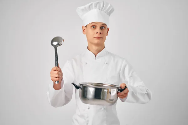 손에 프라이팬을 든 요리사의 제복을 입고 전문 식당에서 요리를 하고 있는 남자 — 스톡 사진
