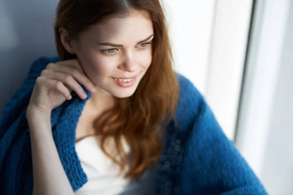 Mooie vrouw zitten in de buurt van het raam met een blauwe ruit — Stockfoto