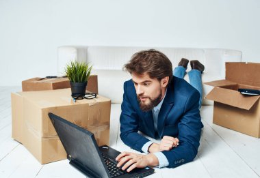 İş adamı dizüstü bilgisayarın önünde kutuları taşır.