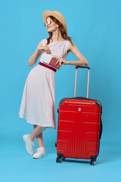 Femme en robe blanche valise rouge destination voyage fond bleu — Photo