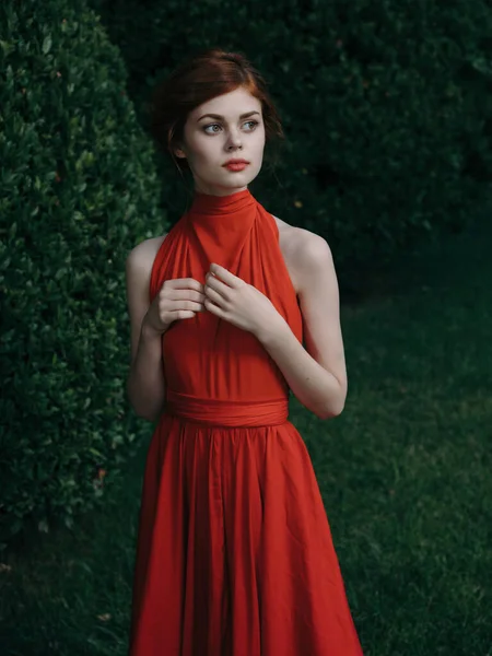 Γυναίκα Κόκκινο Φόρεμα Που Ποζάρει Κοντά Πράσινο Θάμνο Υψηλής Ποιότητας — Φωτογραφία Αρχείου