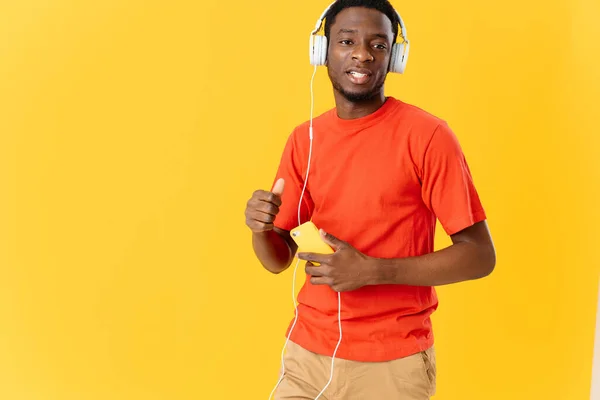 Afro-américain avec écouteurs écoutant de la musique mode divertissement fond jaune — Photo