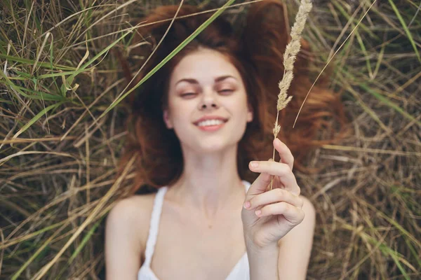 Una mujer en un vestido blanco yace en la hierba con las manos levantadas diversión —  Fotos de Stock