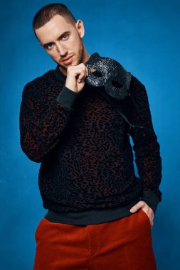 Modern elbiseli bir adam. Siyah yüz maskeli. Mavi arka plan maskeli.