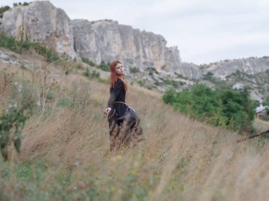 Dağlarda gezen siyah elbiseli bir kadın.