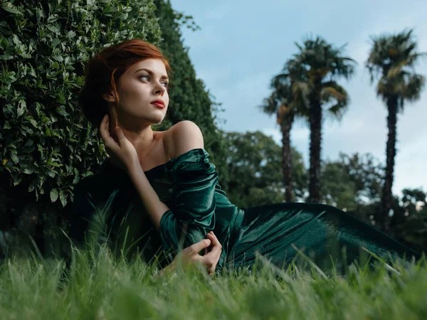 Atractiva mujer en un vestido verde se encuentra en los arbustos de hierba jardín fabulosa vista —  Fotos de Stock