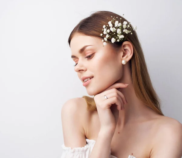 Hermosa mujer atractivo mirar flores en el pelo fondo claro — Foto de Stock