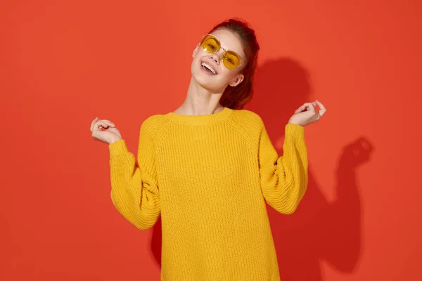 Glad kvinna i gula glasögon håller hennes huvud mode röd bakgrund — Stockfoto