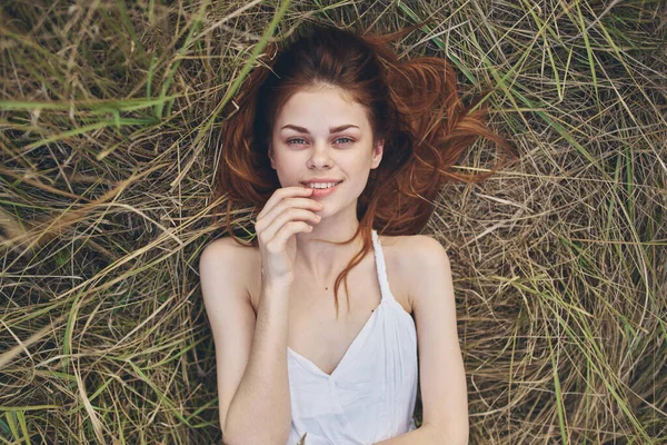 Beyaz elbiseli bir kadın çimenlere uzanmış, gözleri kapalı güneşi dinlendiriyordu. — Stok fotoğraf